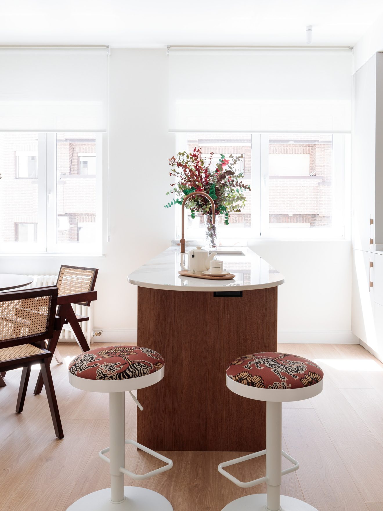 Cocina a medida de Alcasa: isla con encimera clara, taburetes y frente de armarios en roble.